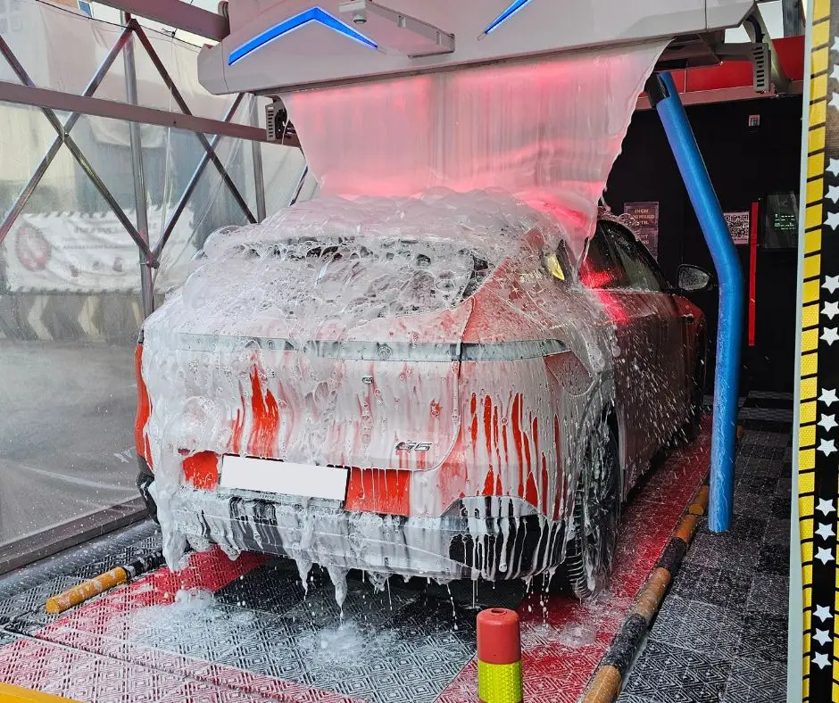 Car covered in thick pink lava foam inside a Driveline wash bay